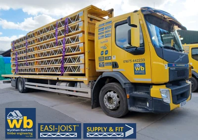 Side angle of a yellow Wyckham Blackwell branded lorry with a full load of easi-joist metal web joists