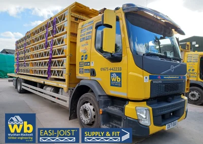 A front-angle of a yellow Wyckham Blackwell branded lorry with a full load of easi-joist metal web joists