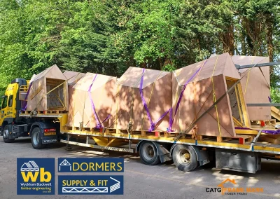 Wyckham Blackwell flatbed truck carrying multiple prefabricated wooden Dormer units strapped with purple webbing.