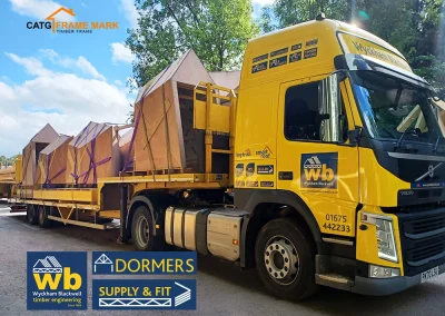 Yellow Wyckham Blackwell flatbed truck carrying pre-built timber Dormers.