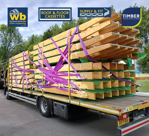 Wyckham Blackwell flatbed lorry carrying stacked prefabricated timber roof cassettes secured with purple straps for delivery.