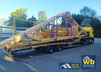 Large wooden Roof Trusses strapped on a yellow Wyckham Blackwell flatbed truck.