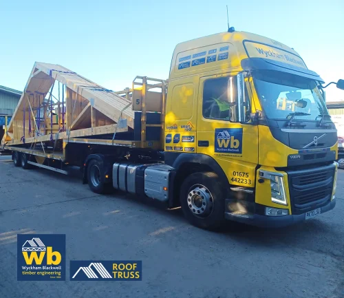 Large wooden Roof Trusses strapped on a yellow Wyckham Blackwell flatbed truck.