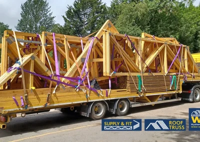 Wyckham Blackwell flatbed lorry loaded with large wooden roof trusses and beams.