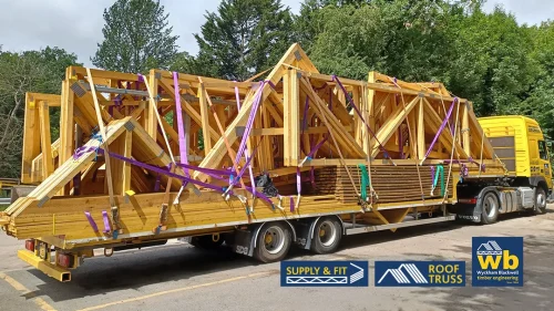 Wyckham Blackwell flatbed lorry loaded with large wooden roof trusses and beams.