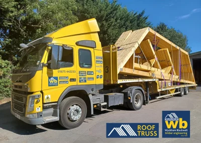 Yellow Wyckham Blackwell flatbed lorry with timber roof truss strapped on the back