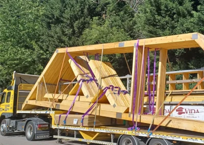 Yellow Wyckham Blackwell flatbed lorry with timber roof truss strapped on the back