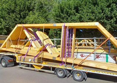 Yellow Wyckham Blackwell flatbed lorry with timber roof truss strapped on the back