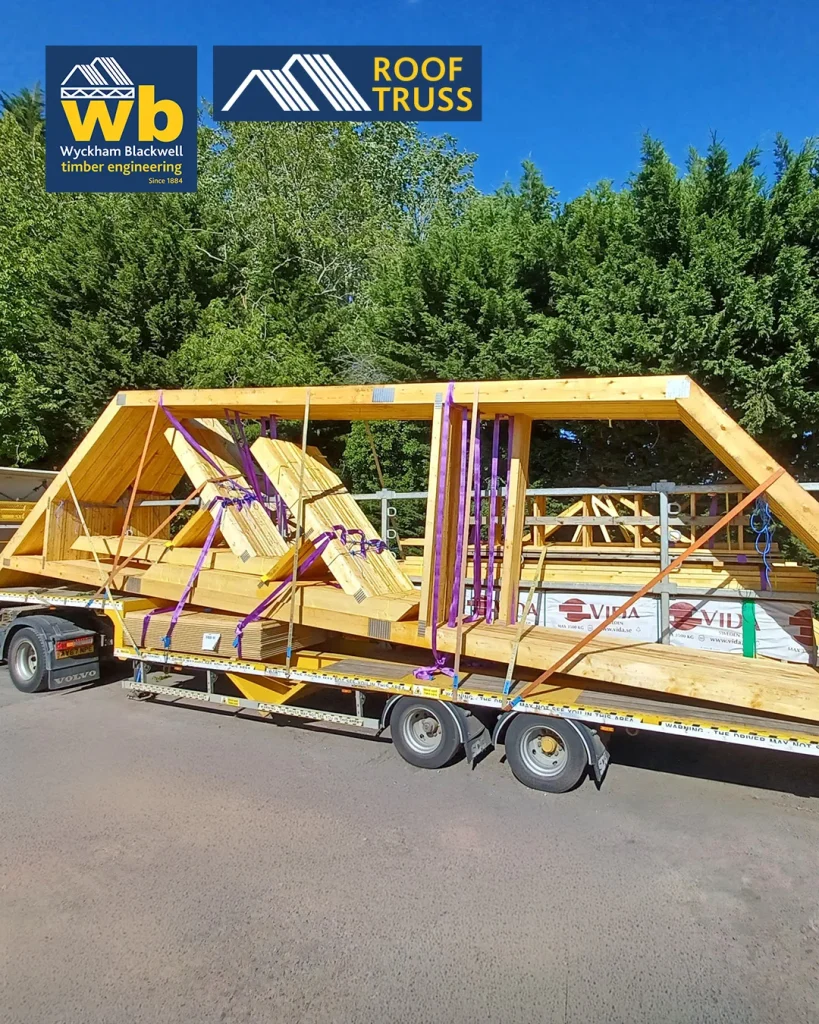 Yellow Wyckham Blackwell flatbed lorry with timber roof truss strapped on the back