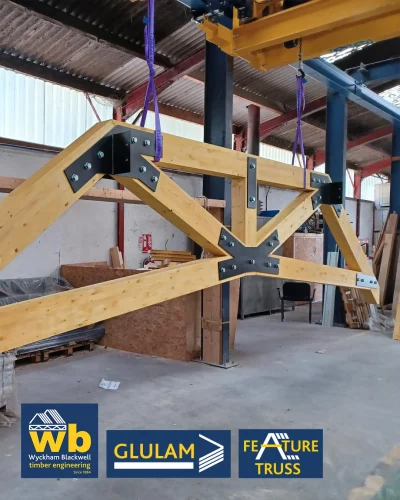 Glulam Feature Trusses joined with bolted black steel plates; Wyckham Blackwell company logo bottom left.