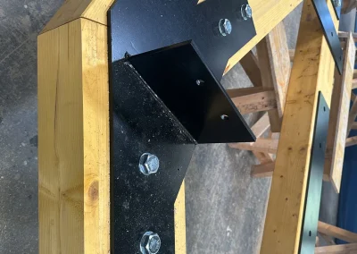 Glulam Feature Truss components on sawhorses in a Wyckham Blackwell workshop with logos in bottom left.