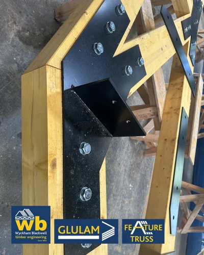 Glulam Feature Truss components on sawhorses in a Wyckham Blackwell workshop with logos in bottom left.